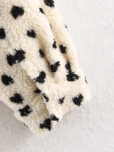 Gros plan du tissu polaire crème à pois noirs avec une texture douce et duveteuse