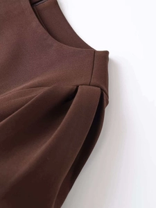 Close-up of pleated waist detail and seam craftsmanship on brown sleeveless dress