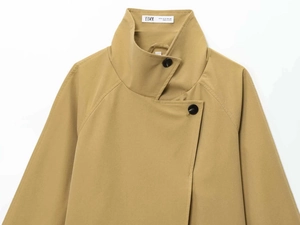 Detail of khaki trench coat with asymmetric buttons and standing collar neck label