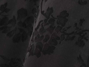 Macro shot of black floral jacquard fabric with elegant vintage leaf patterns and satin finish