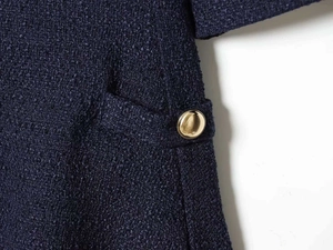 Detail of dark blue tweed dress fabric texture with a polished gold decorative button