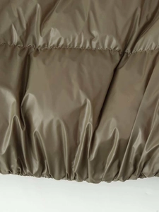 Detailed macro view of olive green quilted jacket fabric with elastic hem and stitching