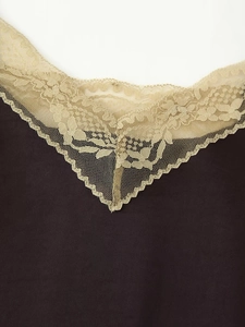 Détail de l'encolure en V avec dentelle beige délicate sur un haut en satin marron foncé