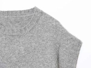 Macro view of grey knit vest showing ribbed crew neck and fine cashmere texture detail