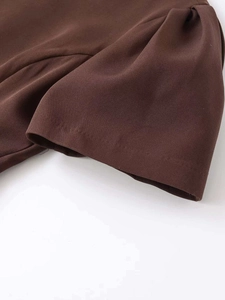 Detail of dark brown mini dress showing pleated puff sleeve and textured fabric