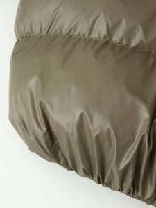 Detailed view of olive green puffer jacket with quilted finish and elastic hem design