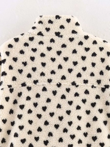 Détail d'une veste en polaire crème avec petits cœurs noirs et col montant élégant