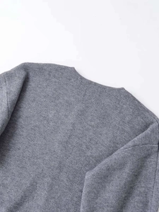 Nahaufnahme der grauen Strickstruktur und Schulternaht eines schlichten Cardigans