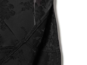 Detail of black jacquard fabric dress featuring floral texture and a side slit design