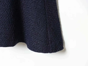 Close-up of navy blue tweed fabric showing dense weave texture and neat stitching details