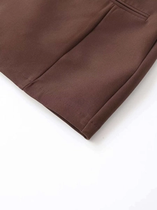 Detail of dark brown mini dress showing pleated pocket and clean hemline stitching