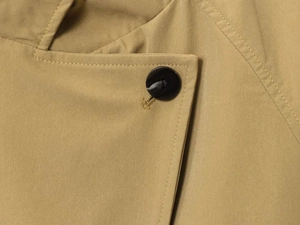 Macro detail of khaki jacket neckline featuring high-density twill fabric and black resin button