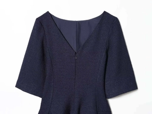 Detail of dark blue tweed dress featuring a deep V-neckline and a hidden zipper closure