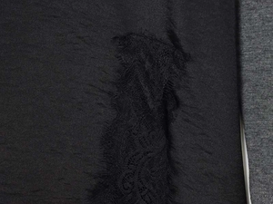 Close-up of black velvet dress fabric featuring intricate lace floral patchwork and stitching
