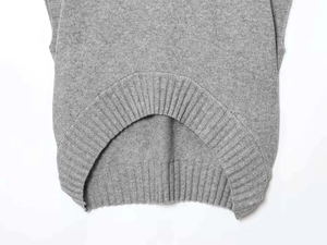 Detail of grey knit vest showing fine ribbed hem and asymmetrical curved cut
