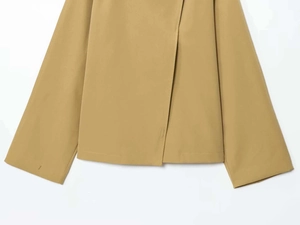 Detailed close-up of khaki jacket featuring asymmetrical hemline and premium fabric texture