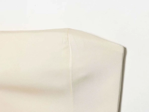 Close-up detail of smooth cream satin fabric with premium feather trim stitching on top