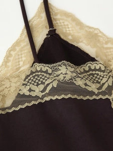 Détail d'un haut en satin marron avec bordure en dentelle florale dorée et fines bretelles