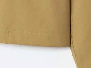 Detail of khaki twill jacket featuring precise single-needle stitching and clean hemline