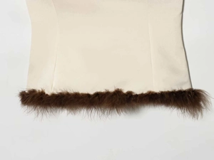 Detailed view of the feather-trimmed hem and stitching on a white strapless top