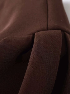 Macro detail of deep brown pleated fabric with precision vertical stitching and texture