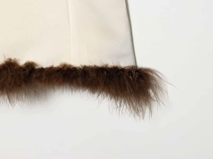 Close-up of ivory woven fabric edge with plush dark brown feather trim detail