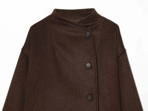 Détail d'un manteau en laine marron chocolat avec col montant et boutons noirs sur tissu texturé