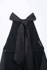 Detail of the elegant black satin halter neck top with a large bow and brand tag