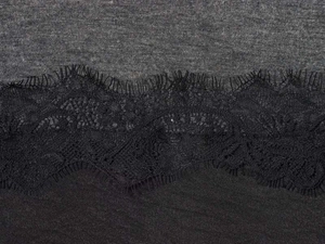 Close-up of black floral lace trim stitched between grey knit and black woven fabrics