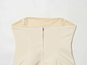 Detail view of the metal zipper closure and hanger loops on the beige strapless top