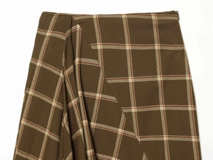 Detailed view of plaid skirt with olive green fabric, asymmetric pleats and side zipper