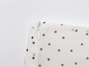 Macro detail of invisible zipper on lightweight white chiffon skirt with black polka dots