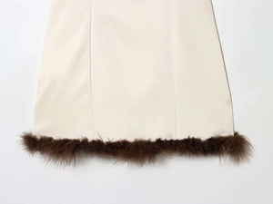 Détail de l'ourlet d'une robe en satin blanc avec une élégante bordure en plumes marron