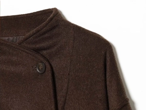 Détail d'un manteau en laine marron chocolat avec col montant asymétrique et bouton texturé