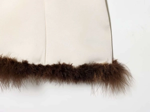 Détail de robe en satin avec bordure élégante en plumes brunes et texture tissée