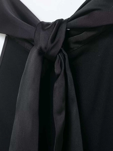 Detailed macro shot of the black satin bow tie and silk texture contrast on a halter top