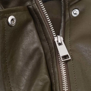 Close-up of olive green faux leather jacket featuring silver metal zipper and snap buttons