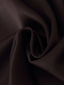 Gros plan sur un tissu satiné marron foncé montrant une texture soyeuse et des plis en spirale