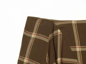 Detailed close-up of brown plaid fabric texture and asymmetric fold on the checkered skirt