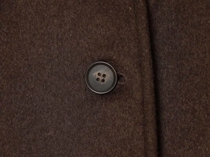 Gros plan détaillé sur la texture du lainage marron foncé avec un bouton à quatre trous