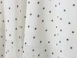 Detailed close-up of white chiffon fabric featuring a classic black polka dot pattern