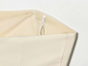 Close-up of precise stitching and satin hanging strap on cream tube top fabric