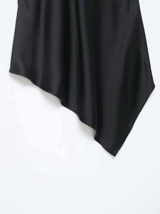 Detailed close-up of smooth black satin fabric with elegant asymmetric draped hemline
