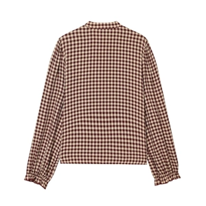 Macro detail of brown checkered shirt fabric featuring ruffled cuffs and stand collar