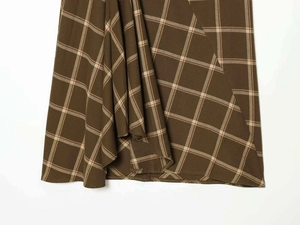 Detail of dark brown plaid fabric with draped pleats and classic check pattern