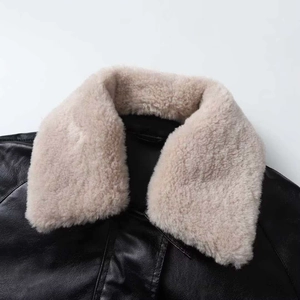 Close-up of black faux leather jacket featuring a beige faux fur collar and shoulder stitching