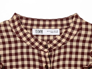 Detail of red-brown gingham shirt showing the collar label and dark round buttons