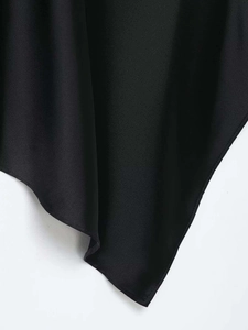 Detail of black satin top featuring a stylish asymmetric hem and smooth fabric texture