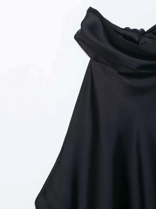Detail of black satin halter top featuring soft neck pleats and premium woven texture