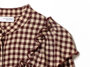 Detail of red gingham shirt with ruffled neckline and high-quality fabric texture